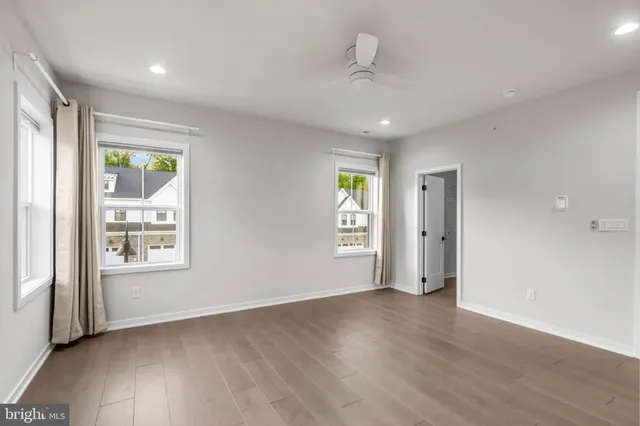 a view of an empty room with a window and wooden floor