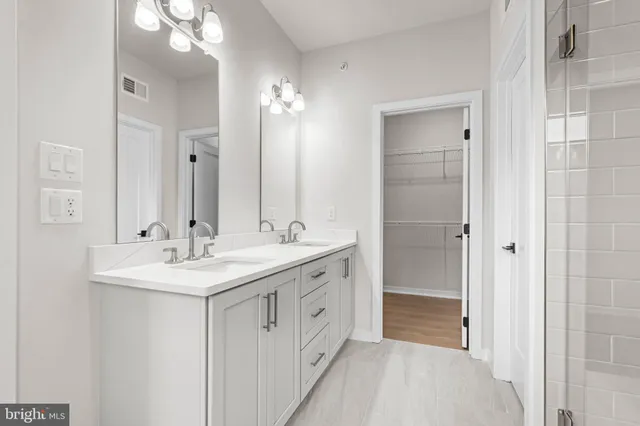 a spacious bathroom with a double vanity sink a mirror and a shower