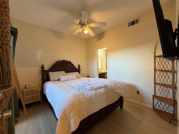 a bedroom with a bed and a flat tv screen on dresser