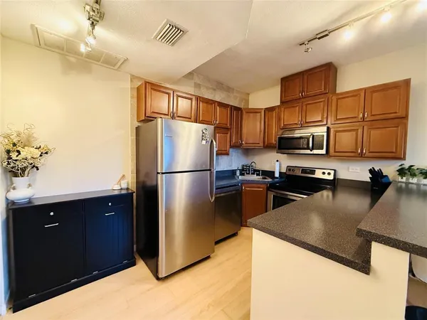 a kitchen with stainless steel appliances granite countertop a refrigerator a stove top oven and a sink