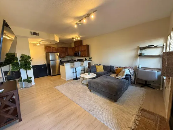 a living room with furniture a flat screen tv and a refrigerator