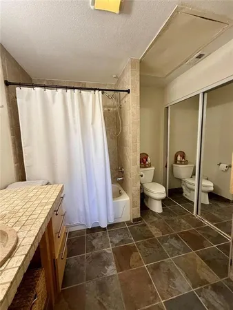 a bathroom with a granite countertop sink a toilet and shower