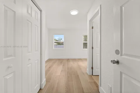 a view of a hallway with wooden floor and a bathroom