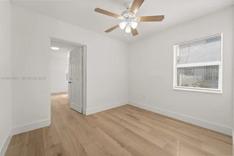 an empty room with wooden floor chandelier fan and windows