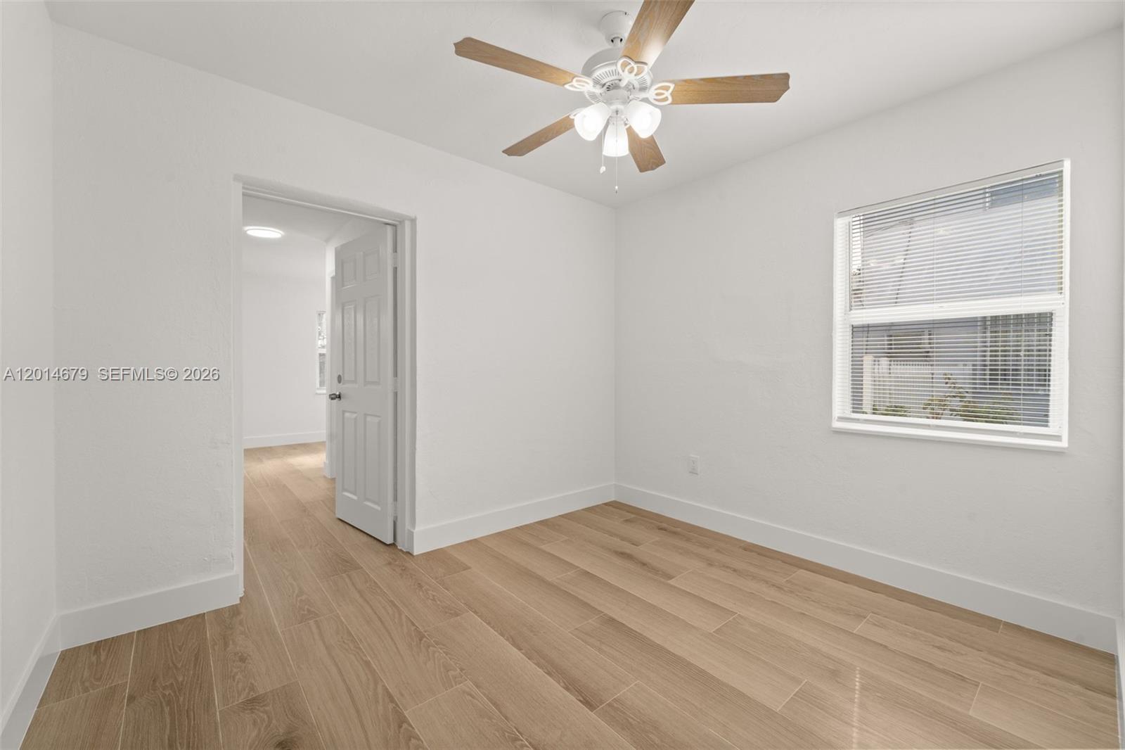 255 Beacom Boulevard, Unit DOWNSTAIRS Miami, FL 33135 - Photo 13 of 36 an empty room with wooden floor chandelier fan and windows