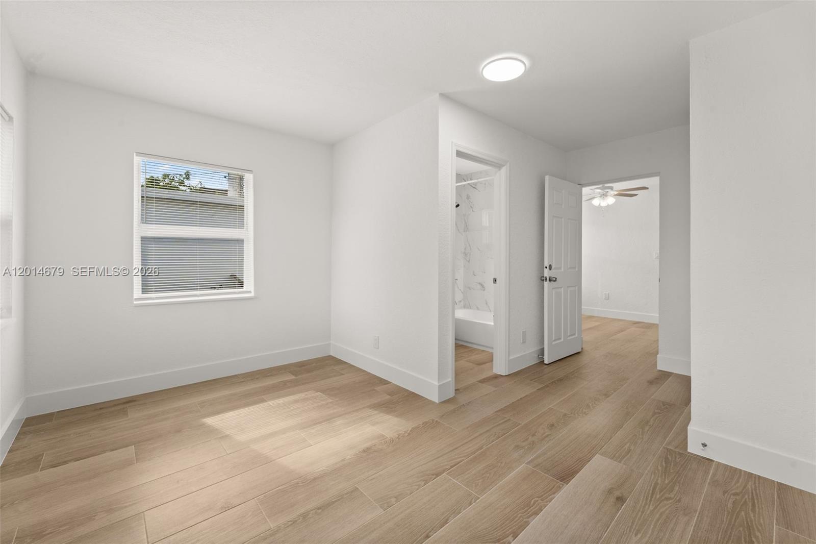 255 Beacom Boulevard, Unit DOWNSTAIRS Miami, FL 33135 - Photo 33 of 36 an empty room with wooden floor cabinet and windows