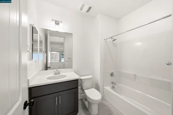 a bathroom with a bathtub shower sink mirror vanity and toilet