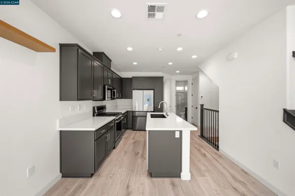 a large kitchen with stainless steel appliances kitchen island a large counter top and a wooden floors