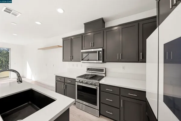 a kitchen with stainless steel appliances a sink dishwasher a stove and a refrigerator with wooden floor