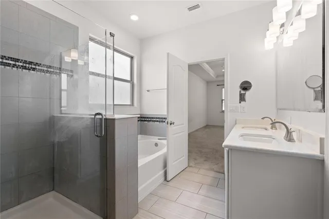 a bathroom with a double vanity sink mirror and bathtub