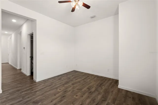 an empty room with a ceiling fan and wooden floor