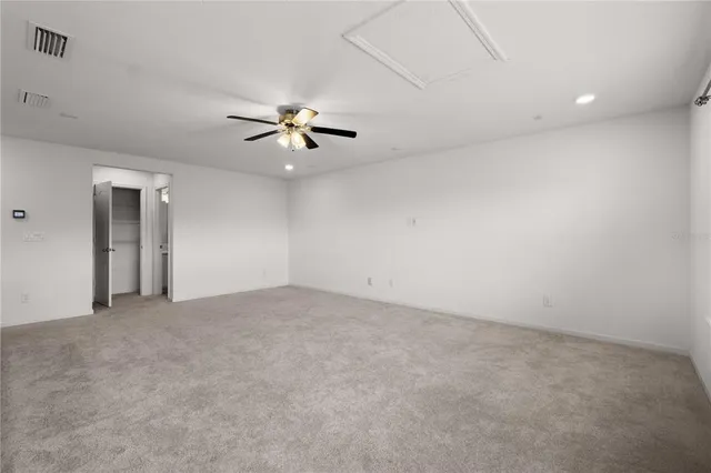 an empty room with chandelier fan and windows