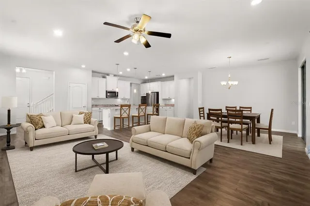 a living room with furniture kitchen view and a wooden floor