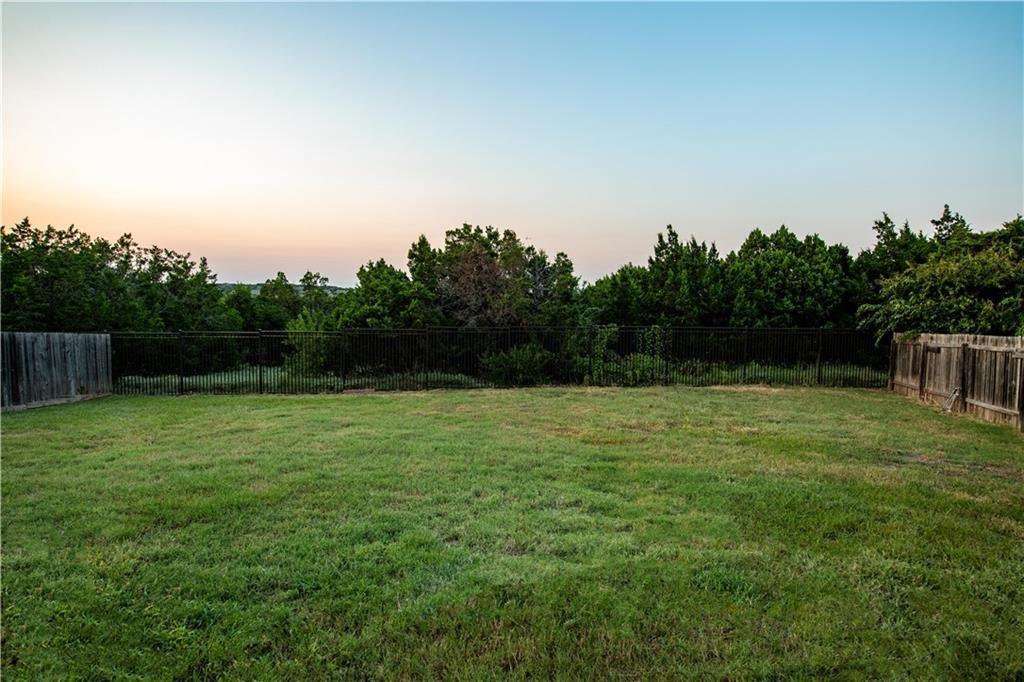 12017 Springs Head Loop Austin, TX 78717 - Photo 23 of 25 A verdant lawn framed by a privacy fence and natural tree line, perfect for outdoor activities.