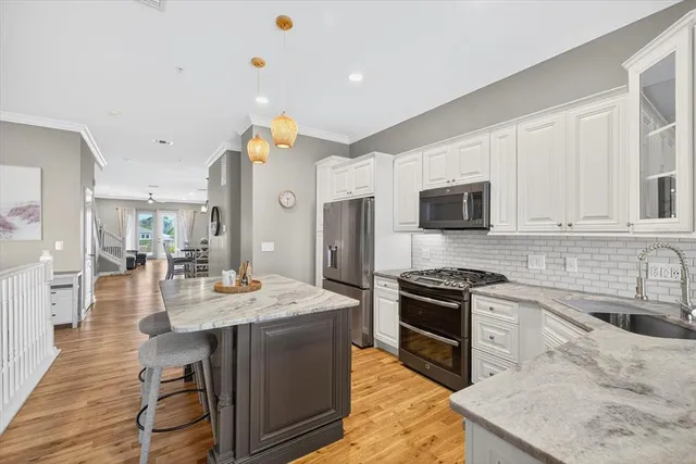 a view of kitchen with kitchen island wooden floor center island and stainless steel appliances