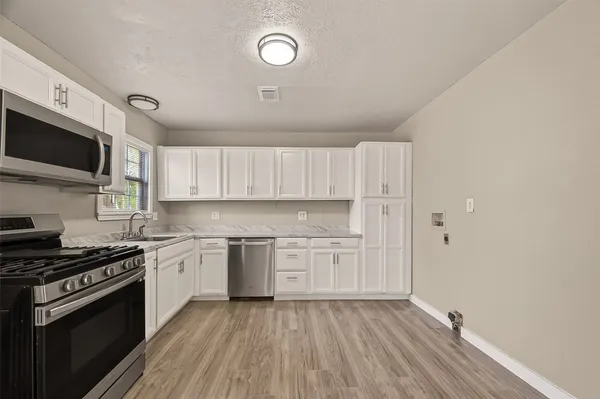 a kitchen with granite countertop a sink cabinets stainless steel appliances and a counter space