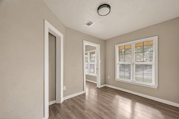an empty room with wooden floor and windows