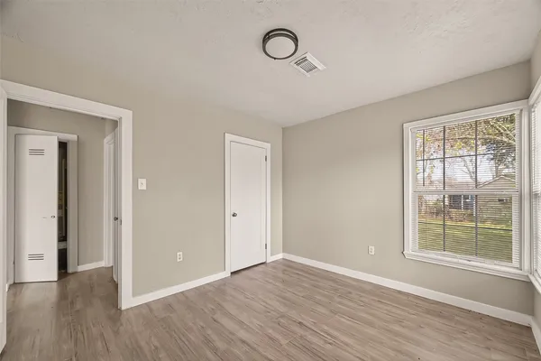 a view of an empty room with wooden floor and window