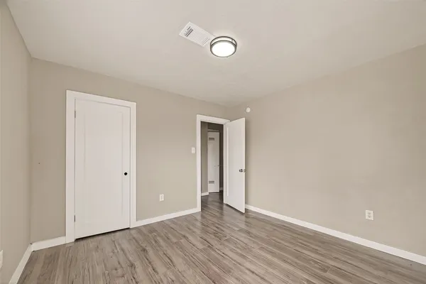 a view of an empty room with wooden floor and closet