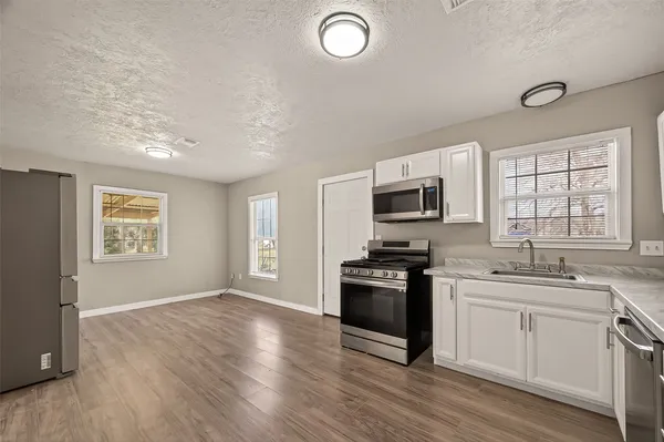 a kitchen with stainless steel appliances granite countertop a stove top oven a sink dishwasher and a microwave oven with wooden floor