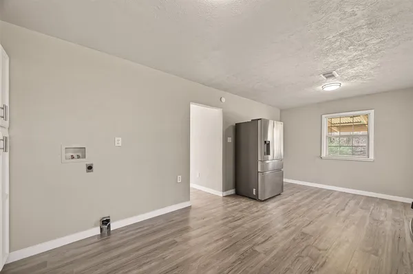 a view of an empty room with wooden floor and closet
