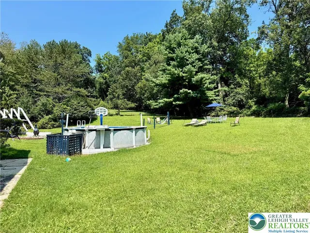 a view of house with a big yard and large trees