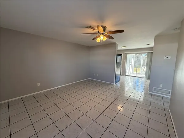 a view of an empty room and chandelier fan