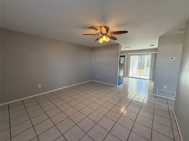 a view of an empty room and chandelier fan
