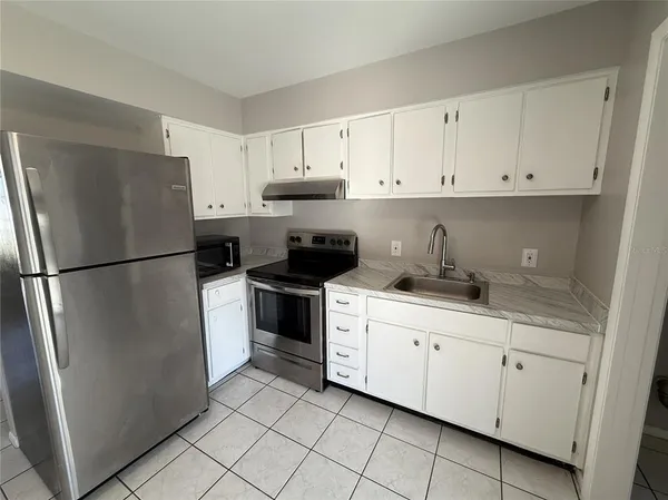 a kitchen with white cabinets and refrigerator