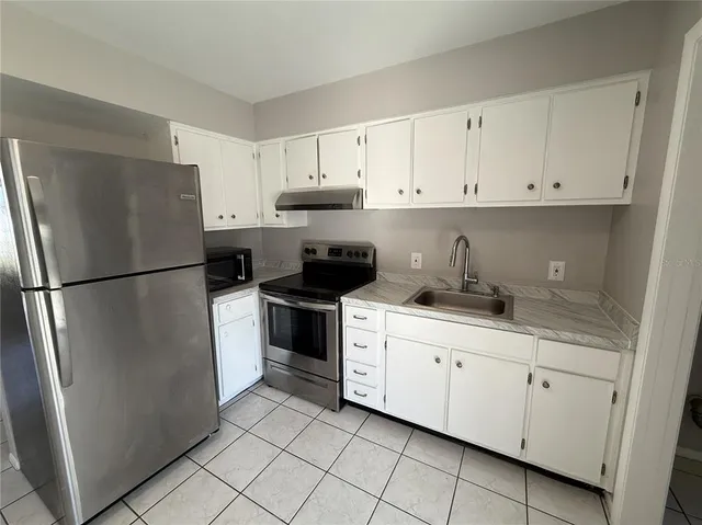 a kitchen with white cabinets and refrigerator