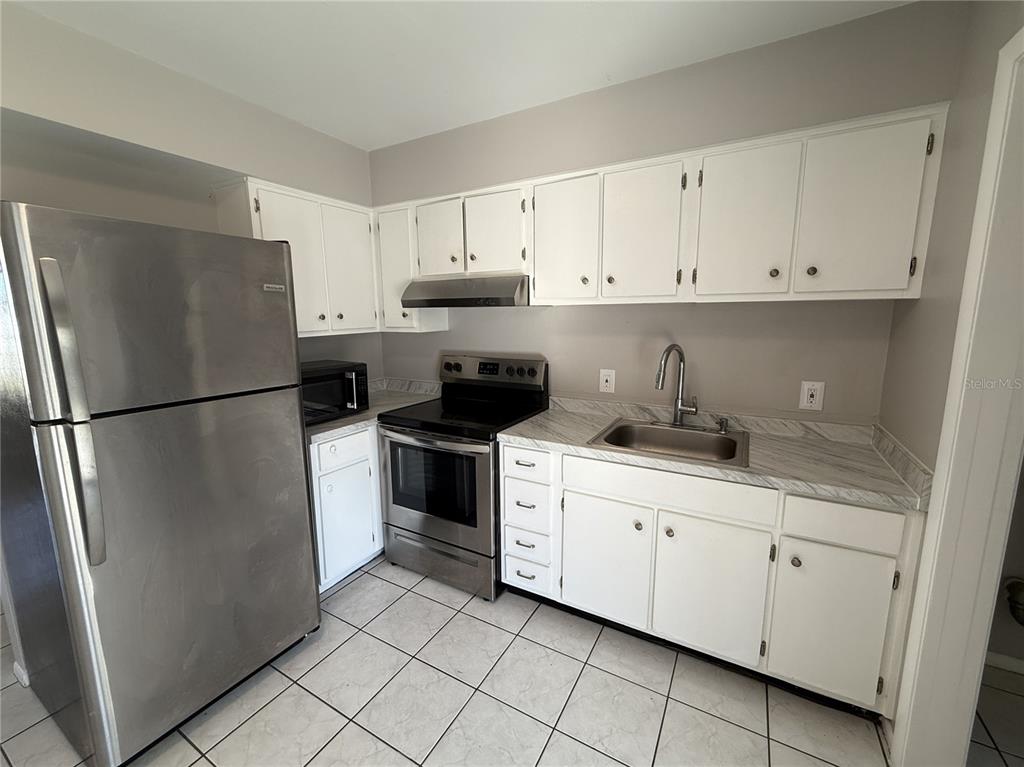 516 Briarwood Road Venice, FL 34293 - Photo 6 of 13 a kitchen with white cabinets and refrigerator