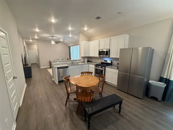 a kitchen with stainless steel appliances a refrigerator a stove a sink a dining table and chairs