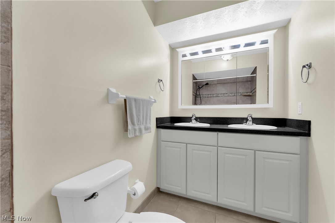 985 Canyon View Road, Unit 108D Northfield, OH 44067 - Photo 16 of 18 Full bathroom featuring double vanity, a tile shower, and light tile patterned flooring