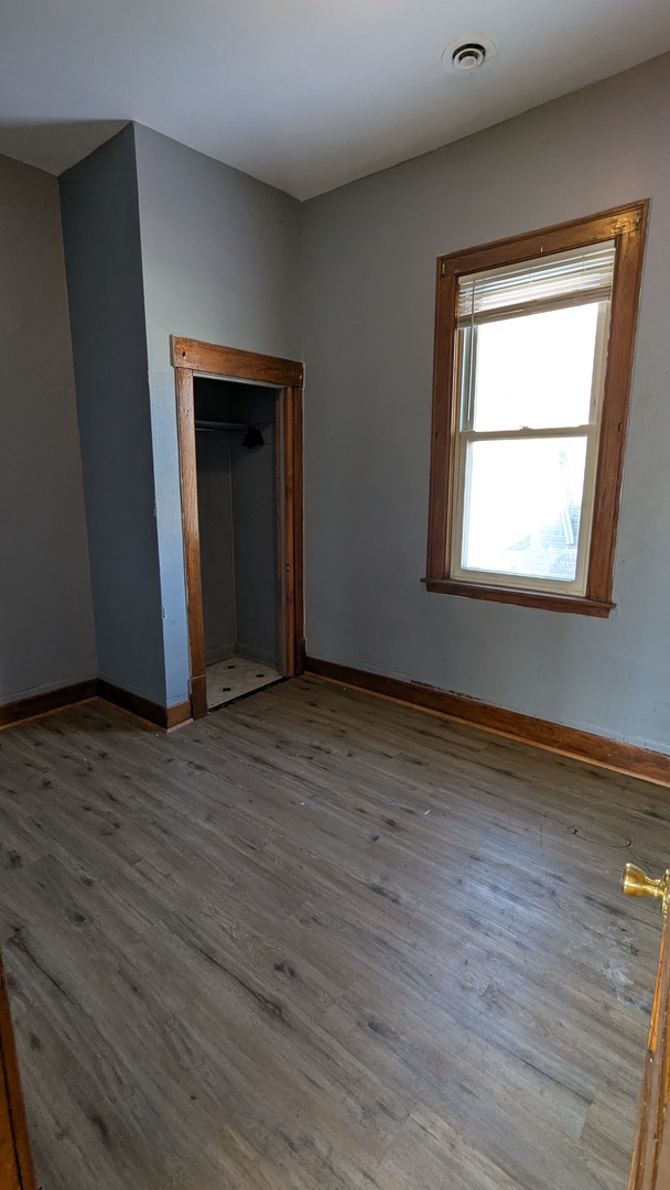 8112 South Exchange Avenue Chicago, IL 60617 - Photo 13 of 35 a view of an empty room with wooden floor and a window