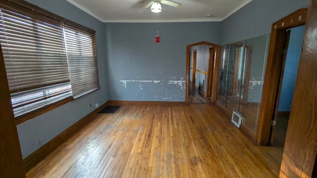 a view of empty room with wooden floor and fan