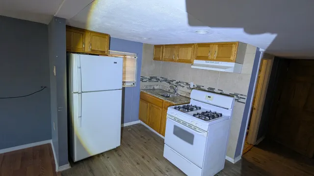 a kitchen with a refrigerator a stove top oven a counter space and wooden floor