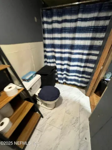 a white toilet sitting next to a shower curtain