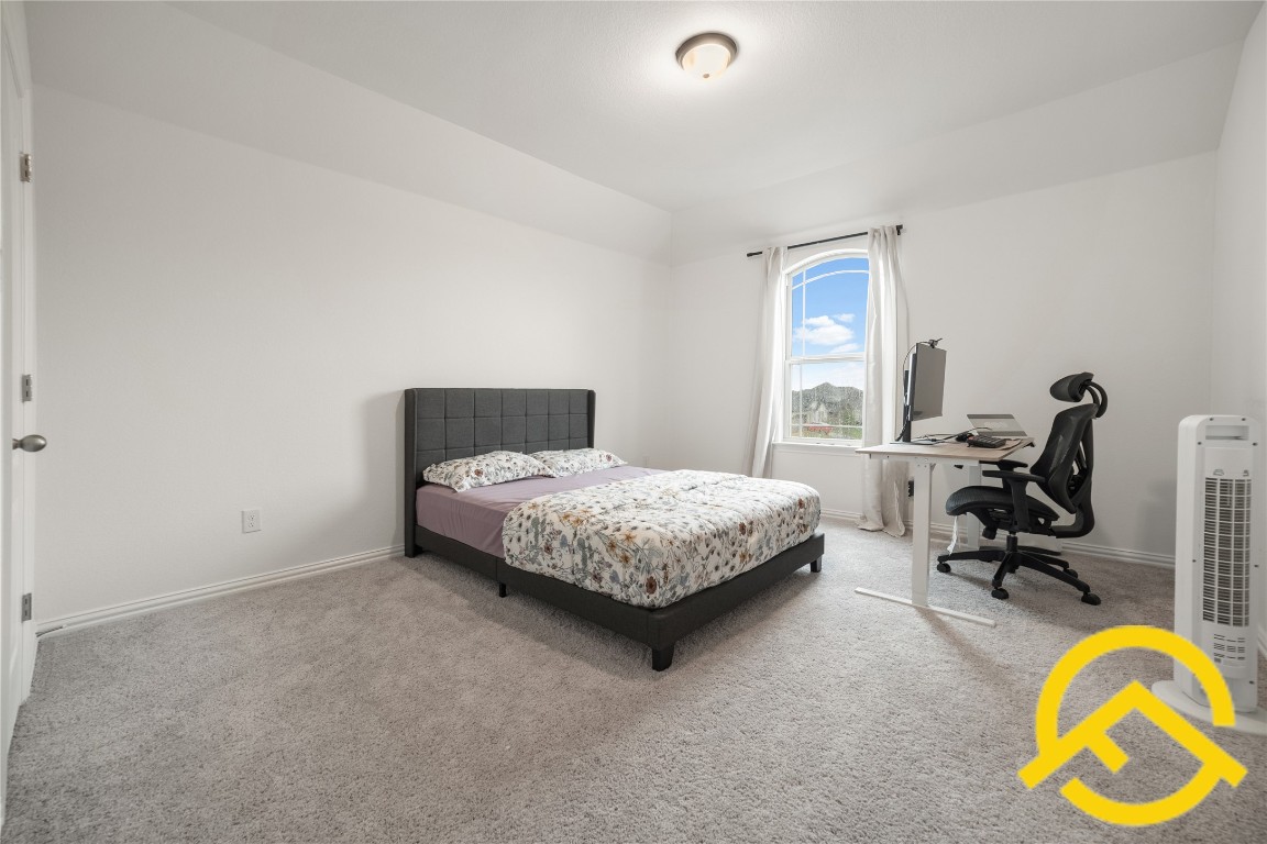 671 Durian Loop Buda, TX 78610 - Photo 14 of 29 a bedroom with a bed a table and a lamp