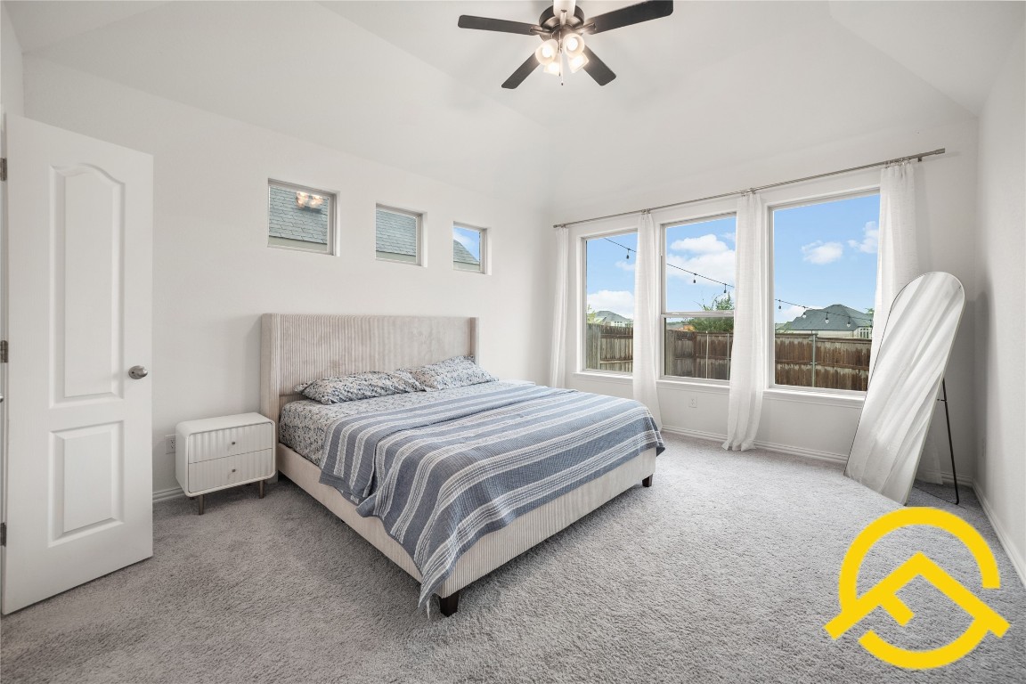 671 Durian Loop Buda, TX 78610 - Photo 18 of 29 a spacious bedroom with a bed a couch and a window