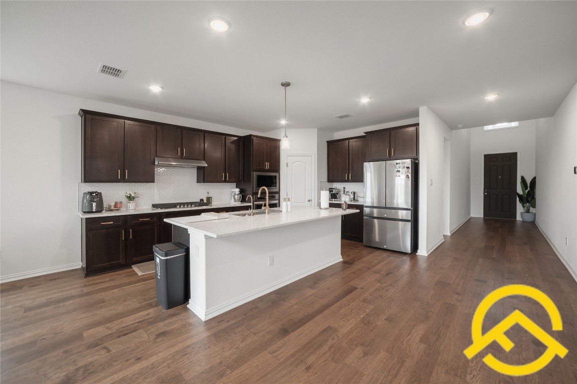 671 Durian Loop Buda, TX 78610 - Photo 3 of 29 a kitchen with kitchen island granite countertop stainless steel appliances cabinets a sink and a counter top space