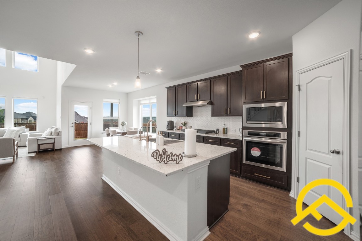 671 Durian Loop Buda, TX 78610 - Photo 4 of 29 a large white kitchen with a stove a oven a kitchen island with a dining table and chairs
