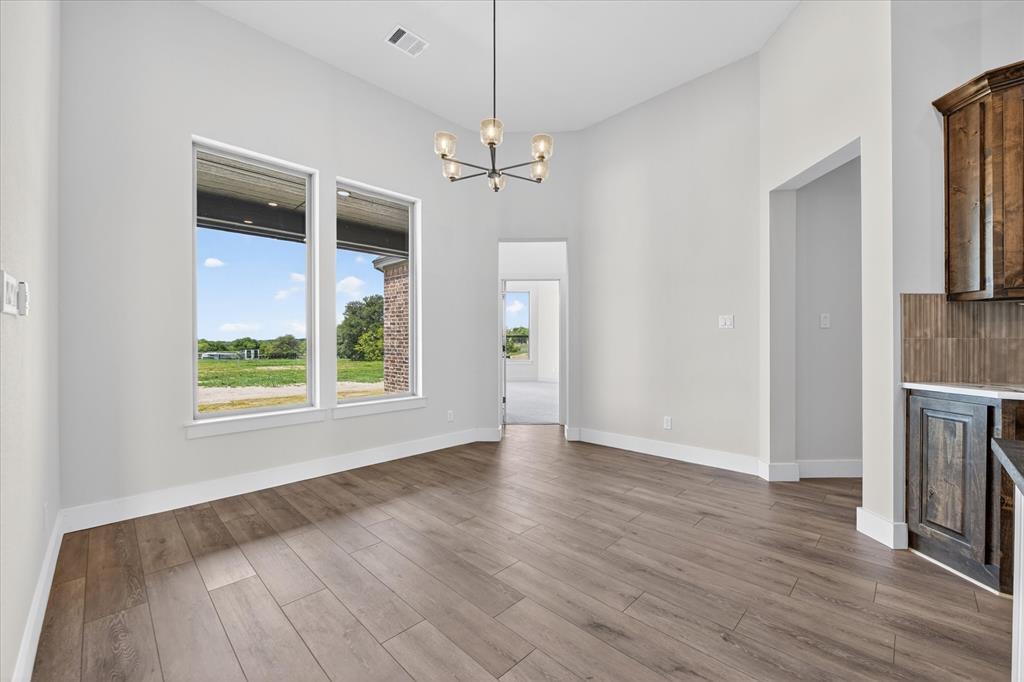 517 Longhorn Lane Springtown, TX 76082 - Photo 11 of 39 Unfurnished dining area with hanging lights, dark wood finished floors, and a high ceiling