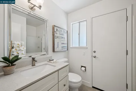 a bathroom with a granite countertop sink a toilet and mirror