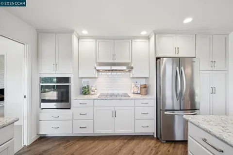 a kitchen with stainless steel appliances granite countertop a refrigerator and a stove top oven