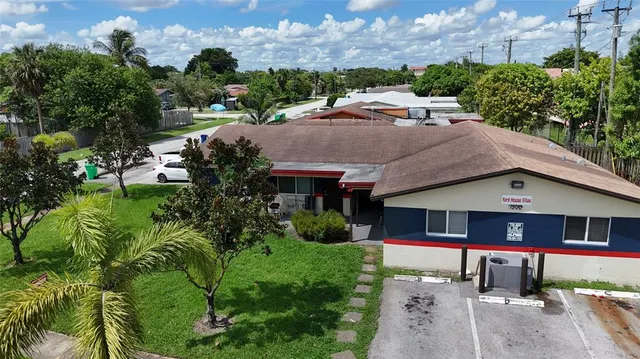 a aerial view of a house with a yard plants and large tree