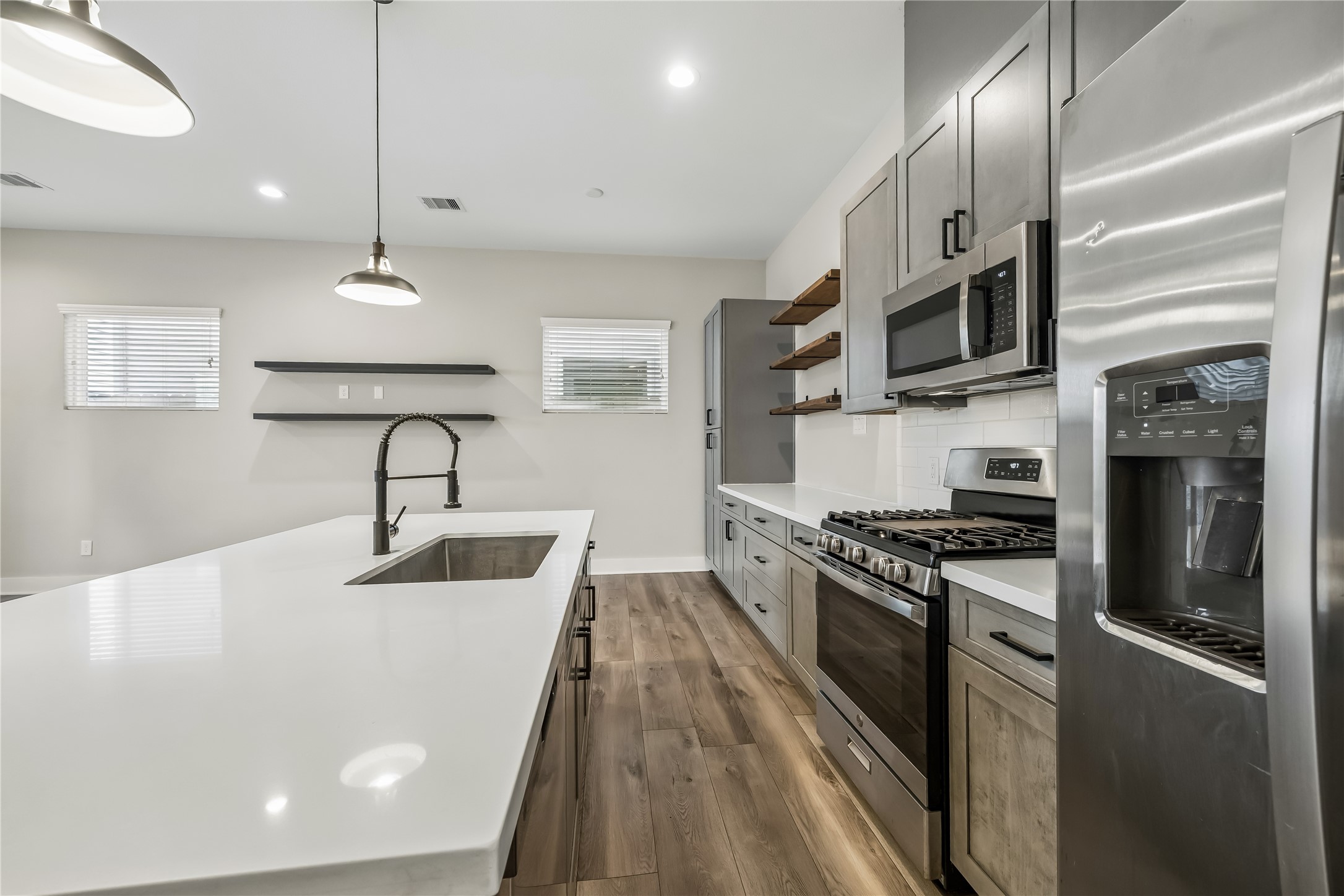 1209 West Tidwell Road Houston, TX 77091 - Photo 6 of 25 The quartz island, large farm sink, and SS appliances make this a useful and alluring kitchen.