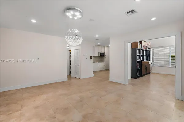 an empty room with kitchen and chandelier