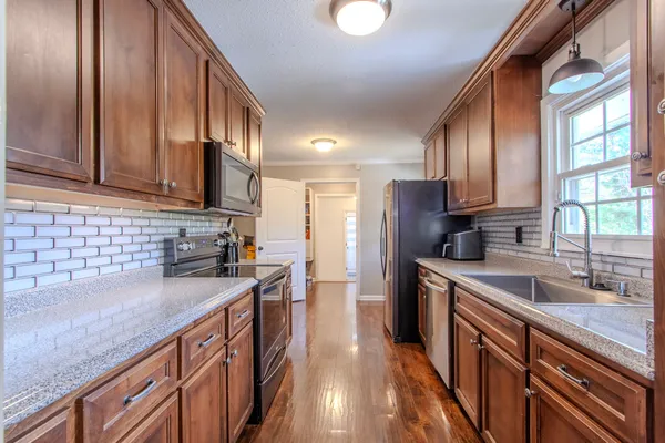 a kitchen with stainless steel appliances granite countertop a sink stove microwave and refrigerator