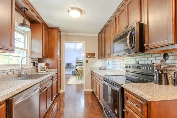 a kitchen with stainless steel appliances granite countertop a sink a stove and a refrigerator