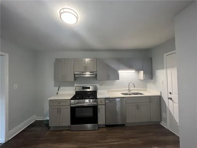 a kitchen with stainless steel appliances a sink a stove a refrigerator cabinets and a window